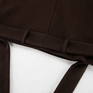 Detailopname van riemlussen op een donkerbruine wollen jas met een getextureerde afwerking