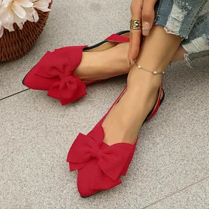 Close-up of elegant red pointed-toe flats featuring a large decorative bow