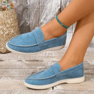 Nahaufnahme von blauen Wildleder-Loafers für Damen, getragen auf einem Holzboden