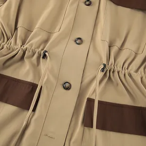 Close-up detail of khaki coat with brown contrast pockets and drawstring waist.