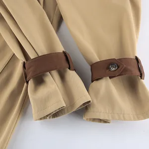 Detailed view of khaki trench coat cuffs featuring brown contrast straps and button design