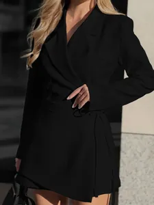 Dettaglio di un elegante abito blazer a portafoglio nero con fiocco in vita.