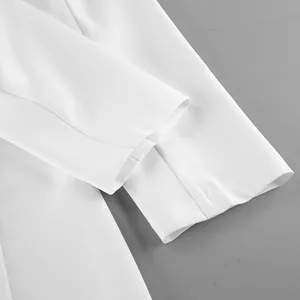 Dettaglio del polsino della manica di un abito blazer bianco con trama del tessuto