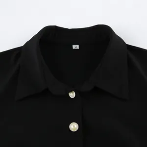 Detailed view of black shirt dress collar featuring decorative white pearl buttons