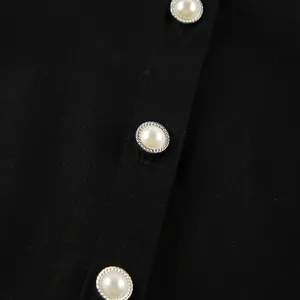 Macro close-up detail showing elegant imitation pearl buttons on black slim-fit shirt dress