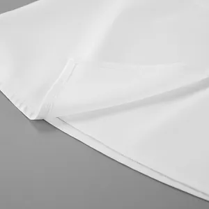 Dettaglio ravvicinato delle cuciture di alta qualità e dell'orlo di questo abito bianco elegante.