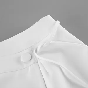Dettaglio vita di un abito blazer bianco con bottone in tessuto ed eleganti lacci