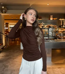 Elegante bruine top met lange mouwen en geplooide details gedragen door een model