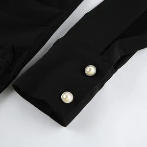 Close-up of black shirt dress sleeve with delicate lace stitching and pearl buttons.