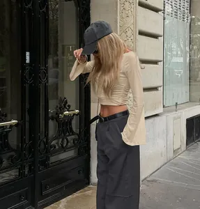 Λεπτομερής προβολή της κομψής σούρας στο πλάι σε κρεμ μπλούζα με καμπάνα μανίκια για γυναίκες