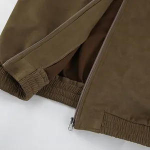 Detailopname van een kaki suède jas met ritssluiting en een elastische geribbelde zoom