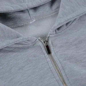 Primer plano detallado de una cremallera metálica en una sudadera con capucha gris vigoré