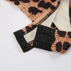 Macro view showing the functional triple snap-button closure on a leopard print bodysuit detail.