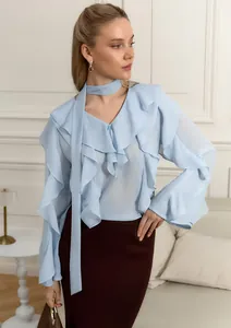 Detalle de blusa azul claro con cuello en V, volantes elegantes y bufanda a juego