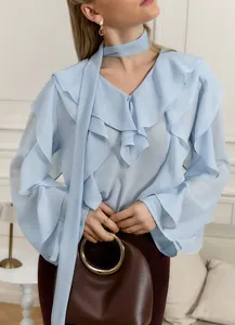 Detalle de blusa de gasa azul claro con volantes, escote en V y lazo elegante