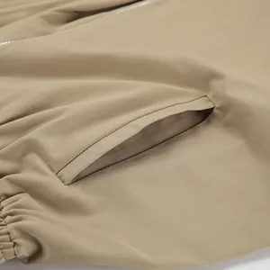 Detailansicht der Tasche und Stoffstruktur eines khakifarbenen Trenchcoats.