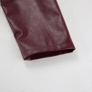 Vue macro du poignet de la manche et de la texture mate d'une veste en cuir bordeaux