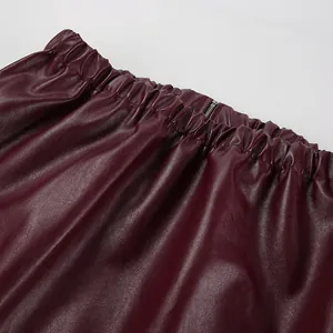 Détail d'une veste en cuir mat bordeaux montrant la taille élastique et la fermeture