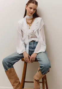 Detalle de los elegantes volantes en esta blusa blanca de manga larga y cuello V.
