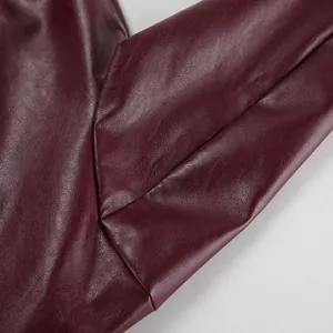 Gros plan d'une veste en cuir mat bordeaux montrant la texture et les détails de couture.