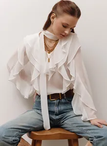 Vista de estilo de vida de blusa blanca con volantes, mangas por capas y lazo en modelo