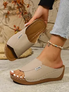 Close-up detail of beige platform wedge slides with stylish decorative stitching.