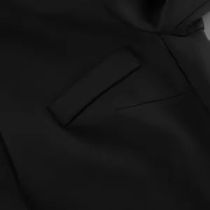 Close-up detail showing the flap pocket and refined stitching of a black blazer