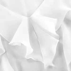 Primer plano de los elegantes volantes de gasa blanca en una blusa de manga larga.