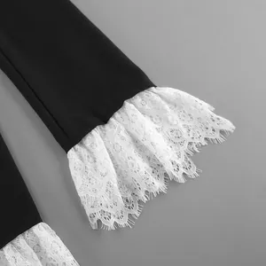 Detailed view of black blazer sleeve featuring elegant white lace flared cuffs.