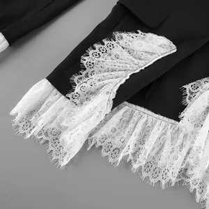 Detailed close-up showing delicate white eyelash lace trim on a black tailored blazer
