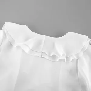 Detalle en primer plano del elegante cuello con volantes de una blusa blanca de manga larga