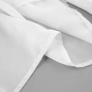 Primer plano de las costuras finas y la tela suave de una blusa blanca con volantes