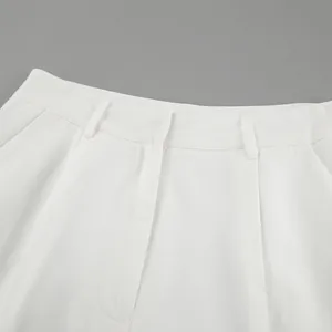 Macro detail of white high-waisted cotton linen pants showing waistband and belt loops