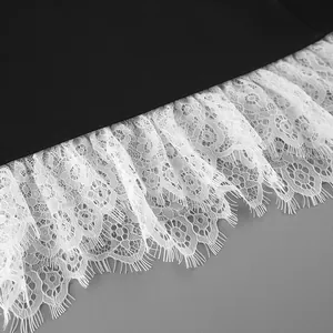 Detail of white lace ruffle hem on a black blazer showing intricate floral texture