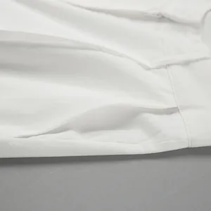 Close-up of pocket and seam detail on white high-waist linen trousers