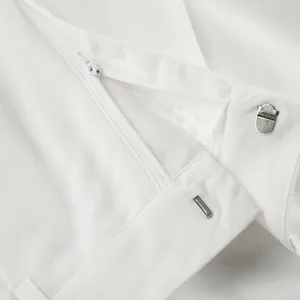 Detailed macro shot showing zipper and metal hook closure on white cotton linen pants