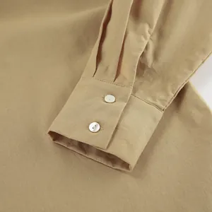 Dettaglio ravvicinato del polsino di una camicia in cotone e lino kaki con bottoni.