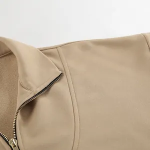 Close-up of golden zipper and khaki stand-up collar detail on a stylish sweatshirt.
