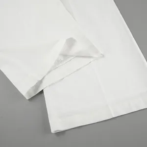 Close-up detail showing the hem and fabric texture of white wide-leg linen trousers