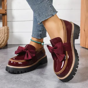 Detail shot of elegant burgundy patent leather bow loafers with thick platform sole.