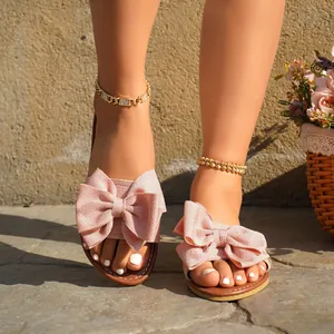 Close-up view of elegant pink bow sandals on feet showing the textured fabric detail
