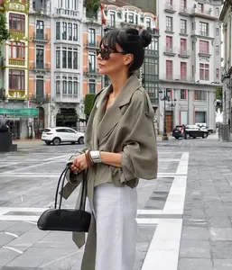 Elegant woman wearing an olive green tie-waist trench coat in a city street.