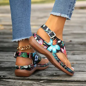 Close-up of ethnic floral embroidery and buckle strap on wedge sandals
