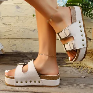 Close-up view of women's beige platform sandals with decorative rivets and metal buckles