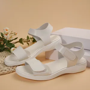 Side view of elegant beige low wedge sandals with adjustable straps on a neutral background.