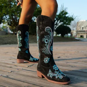 Detailed side view of black knee-high boots featuring intricate blue floral embroidery