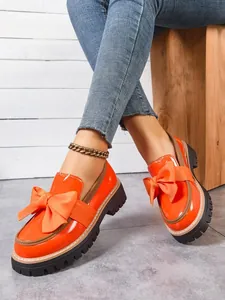 Elegant women's orange patent leather platform loafers featuring an oversized bow detail