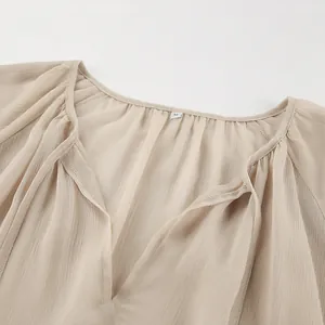 Close-up detail of the V-neckline and sheer fabric texture on a khaki chiffon dress