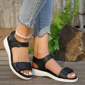 Close-up on-foot view of elegant black wedge sandals with white soles on a wooden deck