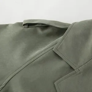 Close-up detail of a green trench coat collar with fine stitching and epaulette.